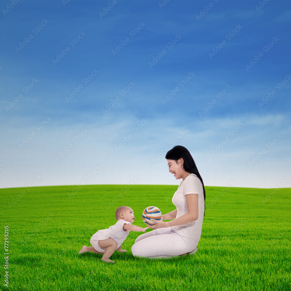 Mother playing with her baby in spring green field Mother playing with her baby in spring green field
