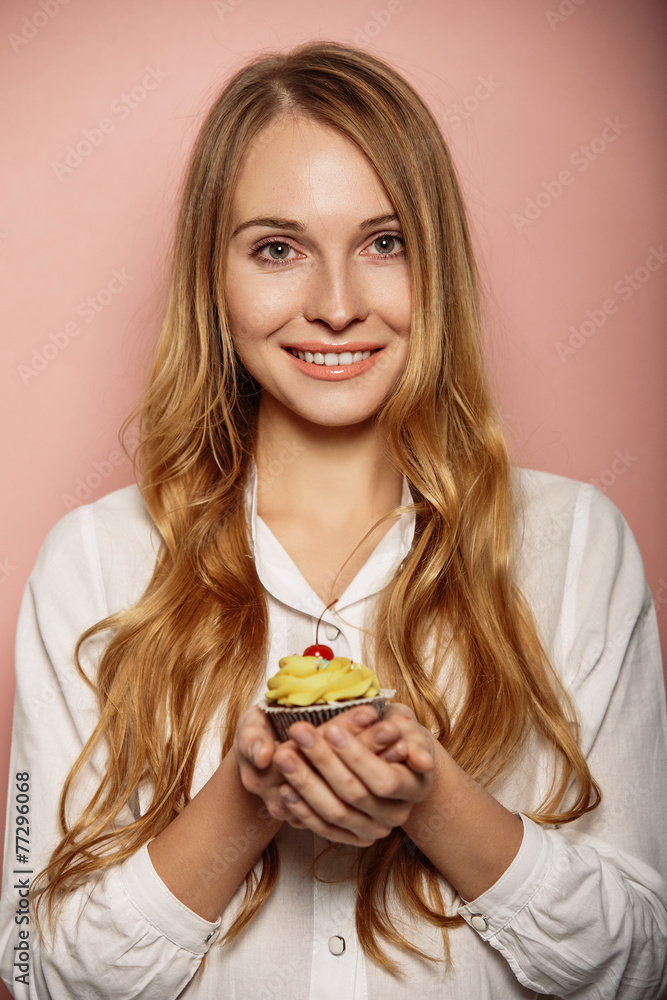 Attractive girl in a white shirt is holding cupcakes
