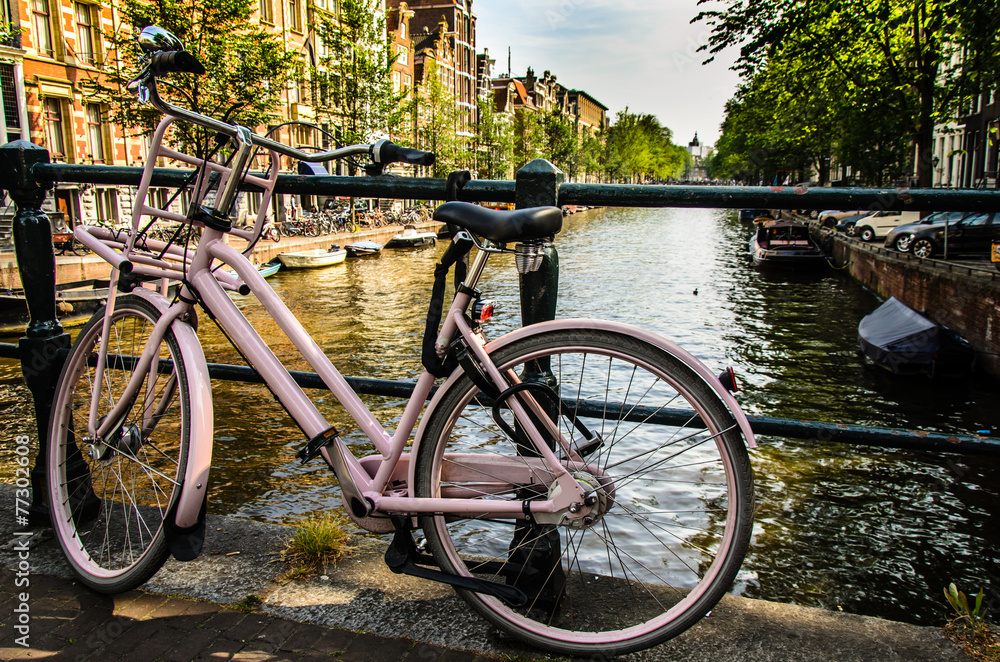 Rosa Damen Fahrrad am Brückengeländer einer Gracht in Amsterdam