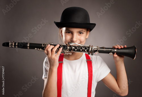 Obraz na plátně little girl playing clarinet on a gray background