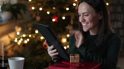 Woman chatting on tablet computer. Christmas tree in background