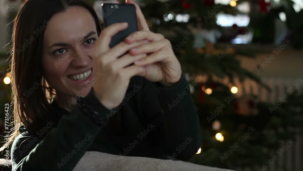 Young pretty woman taking selfie near Christmas tree