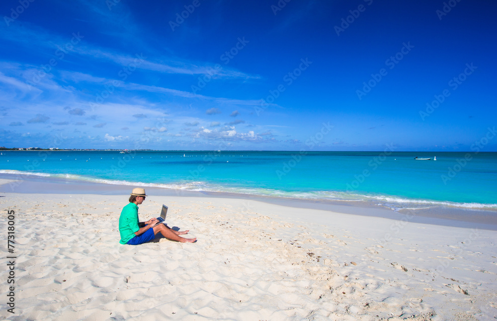 Young man working on laptop at tropical beach