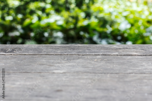 Empty wooden table with blurry green background