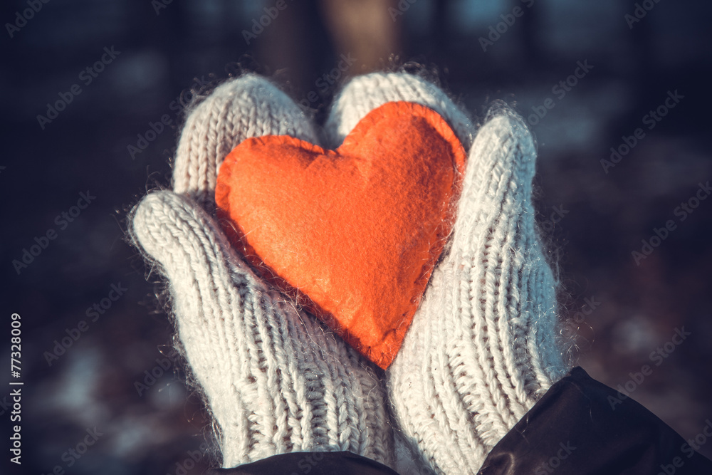 Hands in the mittens holding red heart outdoor, vintage edited