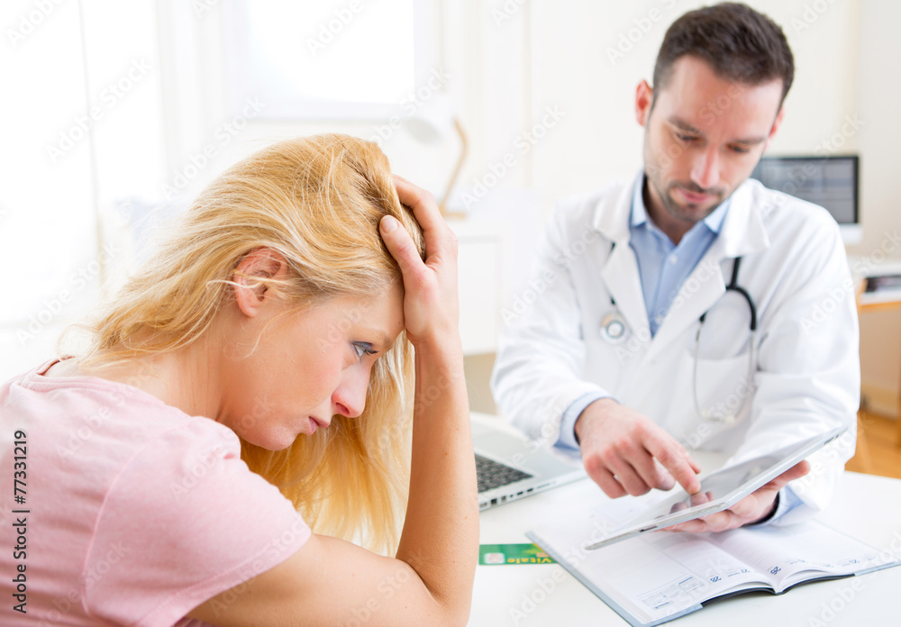 Obraz premium Young doctor showing results on tablet to patient