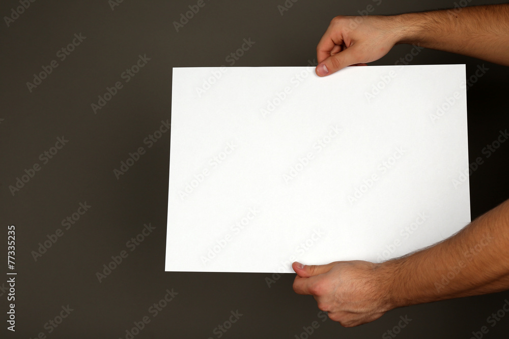 Blank sheet of paper in male hands on dark background Blank sheet of paper in male hands on dark background