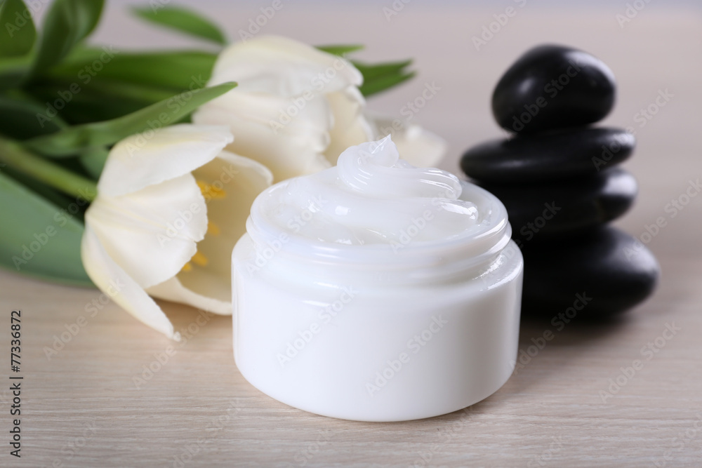Cosmetic cream with flowers and spa stones on wooden background Cosmetic cream with flowers and spa stones on wooden background