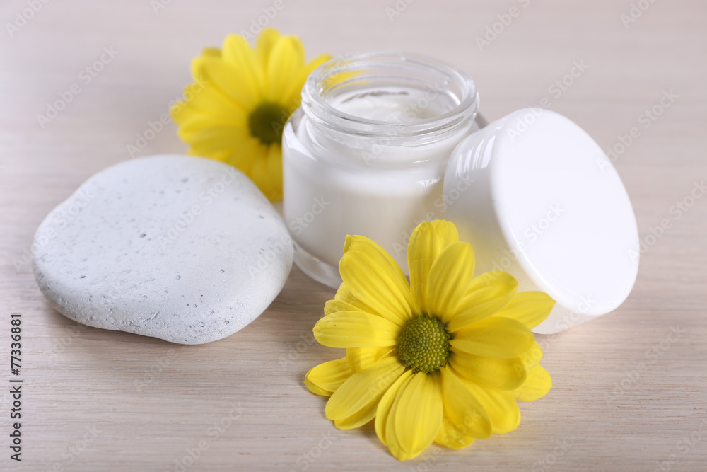Cosmetic cream with flowers and spa stones on wooden background Cosmetic cream with flowers and spa stones on wooden background