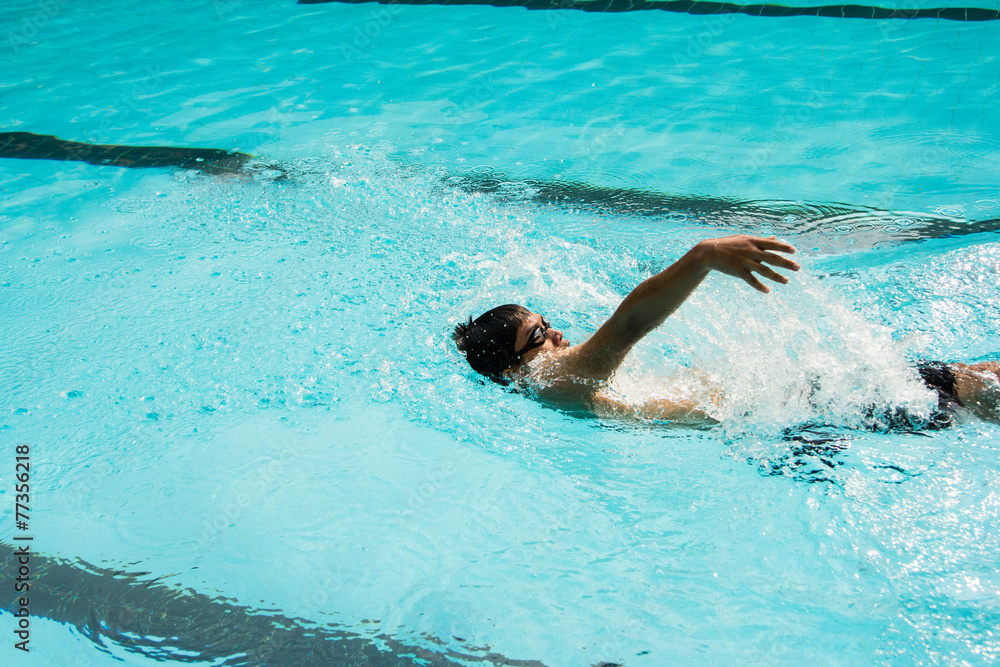 young man swimming in backstroke in a pool.