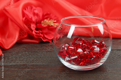 red decorative stones and red silk fabric on wooden background