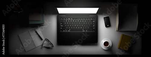 Top view of workspace with laptop and other elements on table.