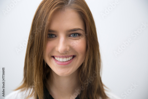 Closeup portrait of a young smiling woman over gray background