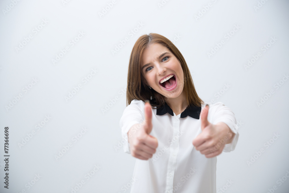 Fototapeta premium Portrait of a laughing woman with thumb up over gray background