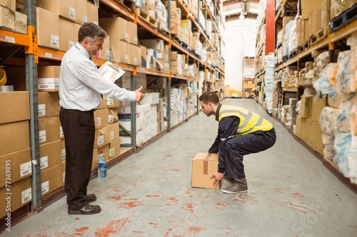 Manager watching worker carrying boxes photo