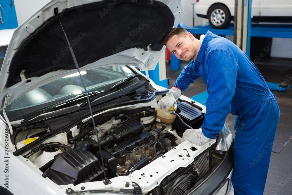 Smiling mechanic working on car Smiling mechanic working on car