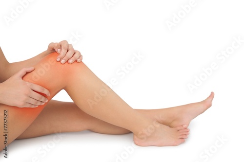 Young woman sitting on floor touching her injured
