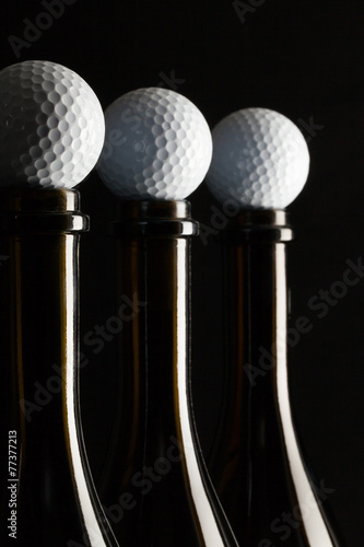 Silhouettes of elegant wine bottles with golf balls