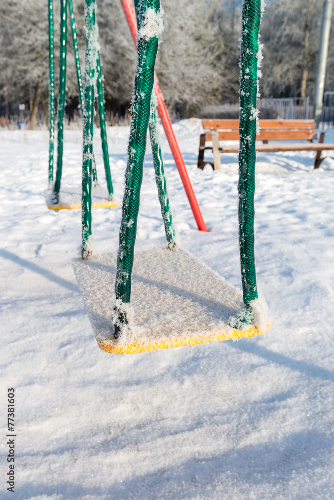 snow covered swing and slide at playground in winter snow covered swing and slide at playground in winter