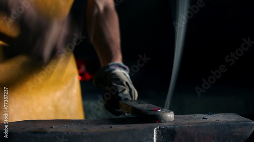 Close up slide shot of blacksmith who shapes metal into final shape photo