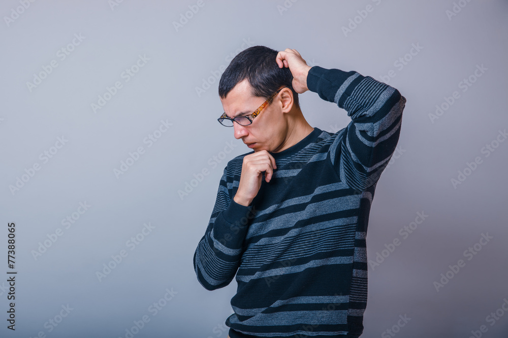male of European appearance brunet thinking on a gray background male of European appearance brunet thinking on a gray background
