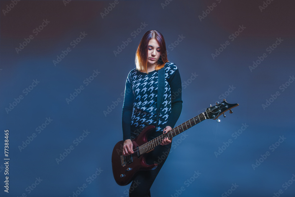 European-looking girl playing guitar on a gray background European-looking girl playing guitar on a gray background