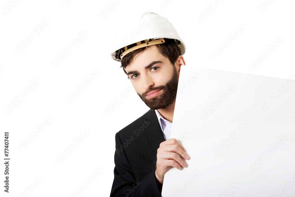 Handsome engineer in helmet holding empty banner.