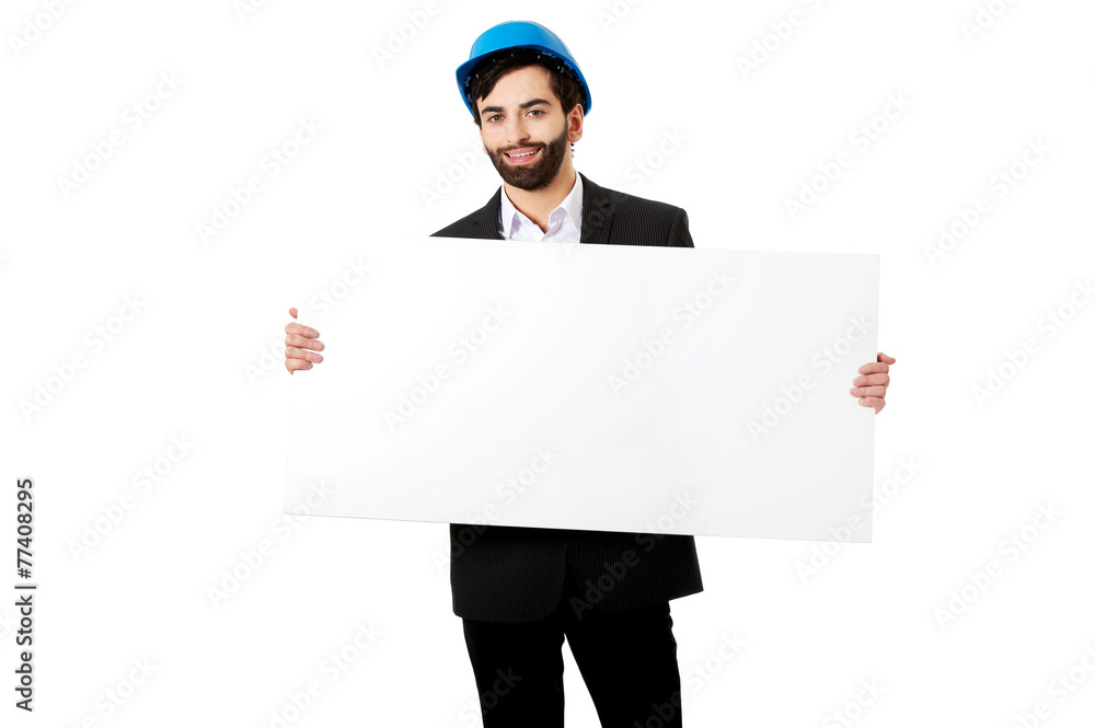 Handsome engineer in helmet holding empty banner. Handsome engineer in helmet holding empty banner.