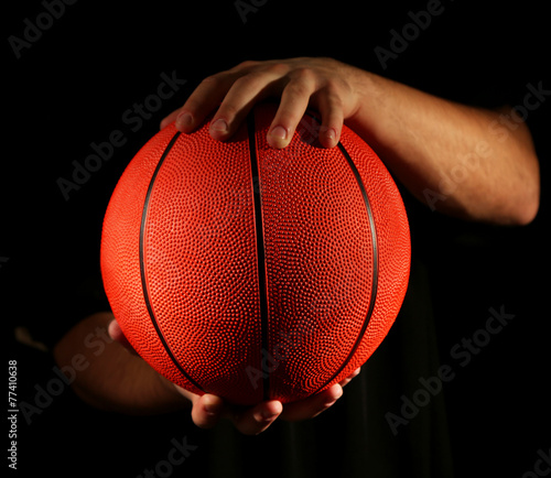 Basketball player holding ball, on dark background © Africa Studio