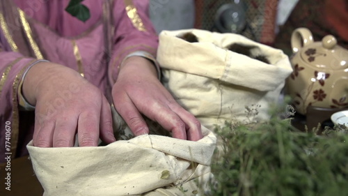 Female hands take herbs from the sack and slowly throw it back  photo