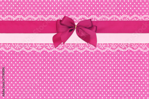 Pink polka dot textile background with ribbons and bow