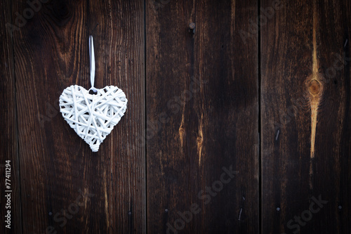 White wicker heart on wooden background