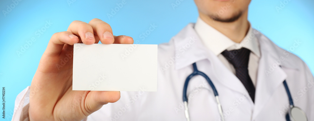Male doctor with card on blue background Male doctor with card on blue background