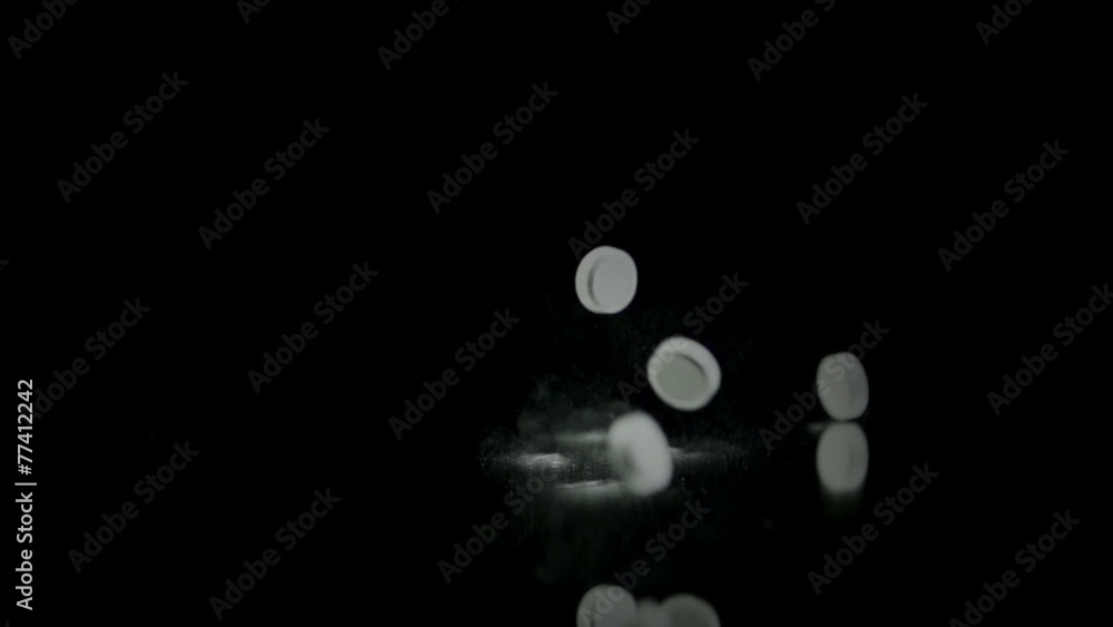 Tablets tall and bounce around in slow motion on black background Tablets tall and bounce around in slow motion on black background