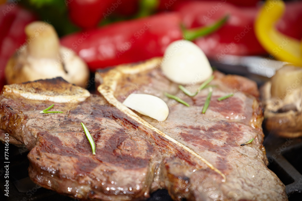 T-bone steak on the barbecue grill with vegetable spears in the
