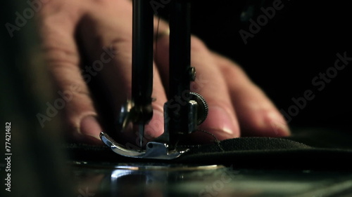 Close up shot of a tailor behind a sewing machine photo