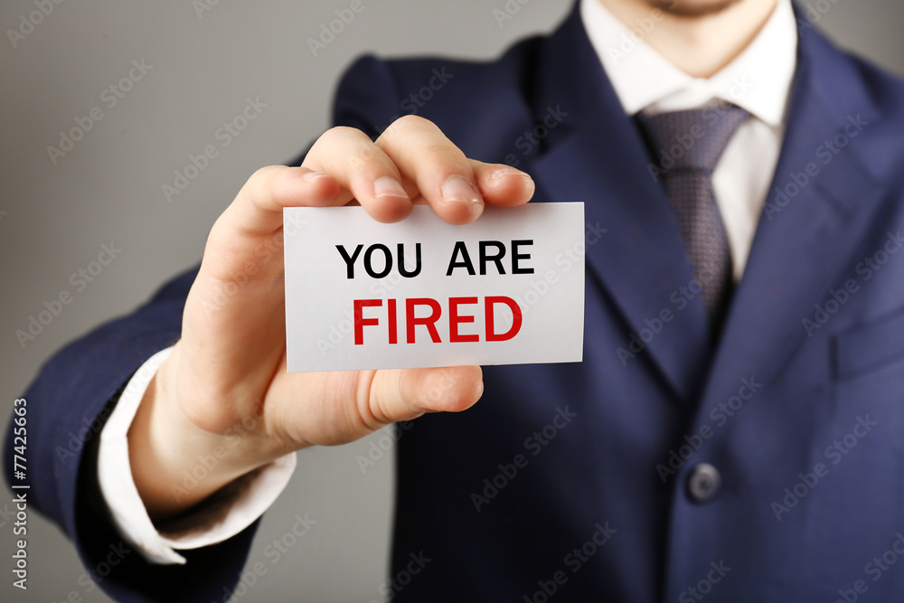 Businessman holding card with text You are fired Businessman holding card with text You are fired