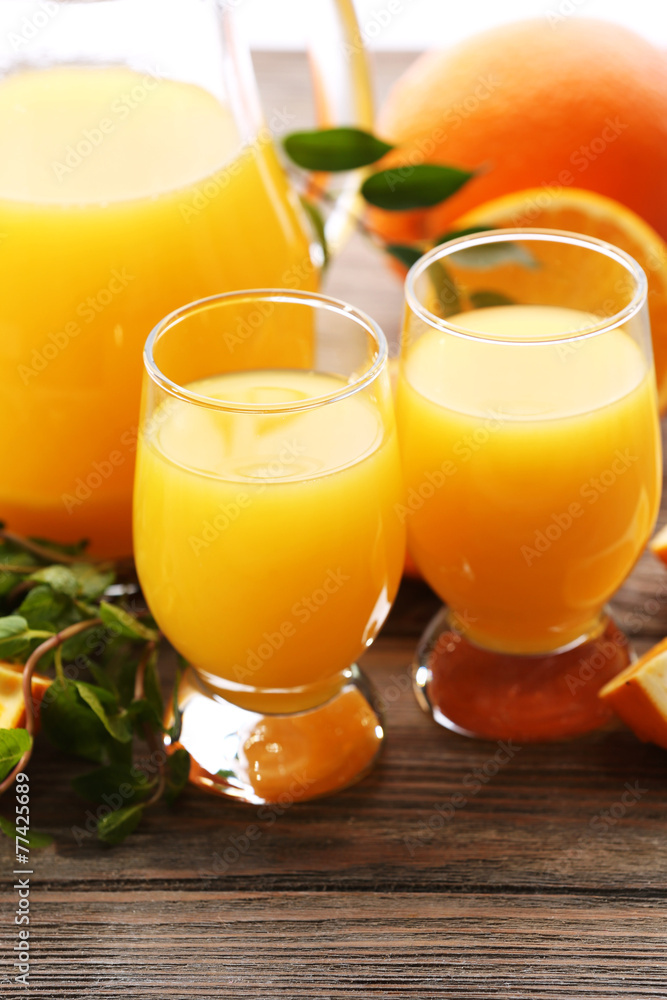Glass of orange juice and slices on wooden table background