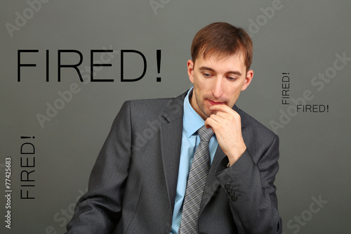 Sad fired office worker on gray wall background