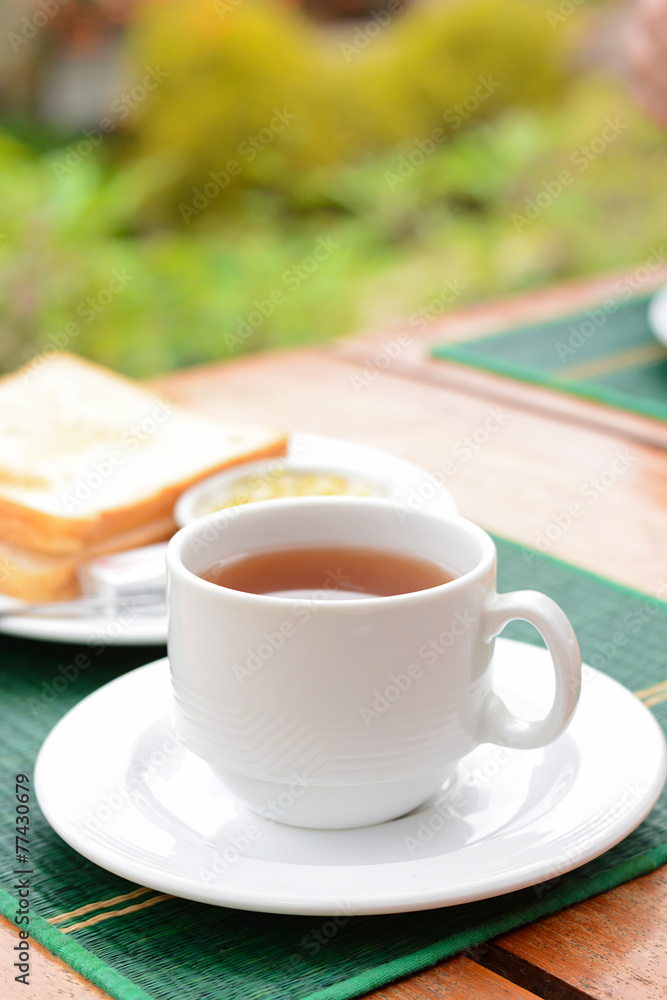 Hot tea in white cup with sliced bread on green mat Hot tea in white cup with sliced bread on green mat