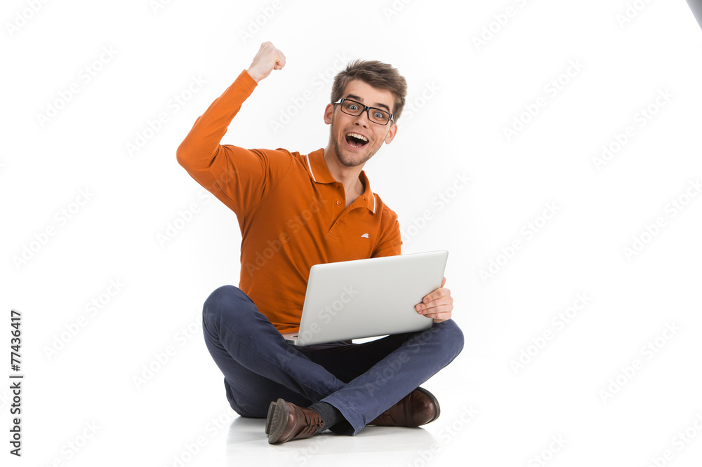 Handsome man cheering at camera with laptop.