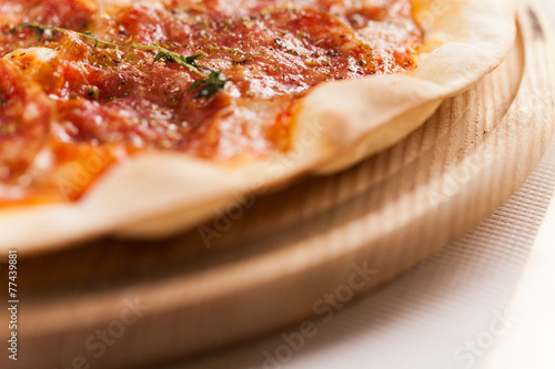 Pizza with ham and tomatoes on wooden background.