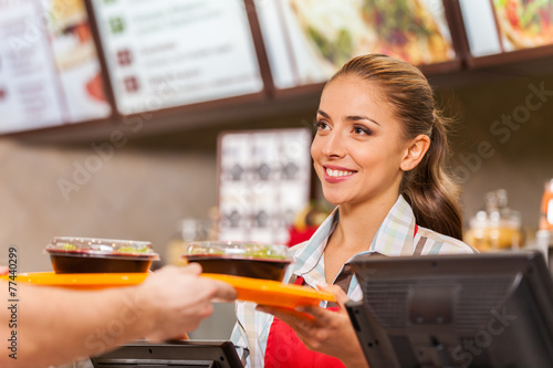 Restaurant worker serving two fast food meals with smile.