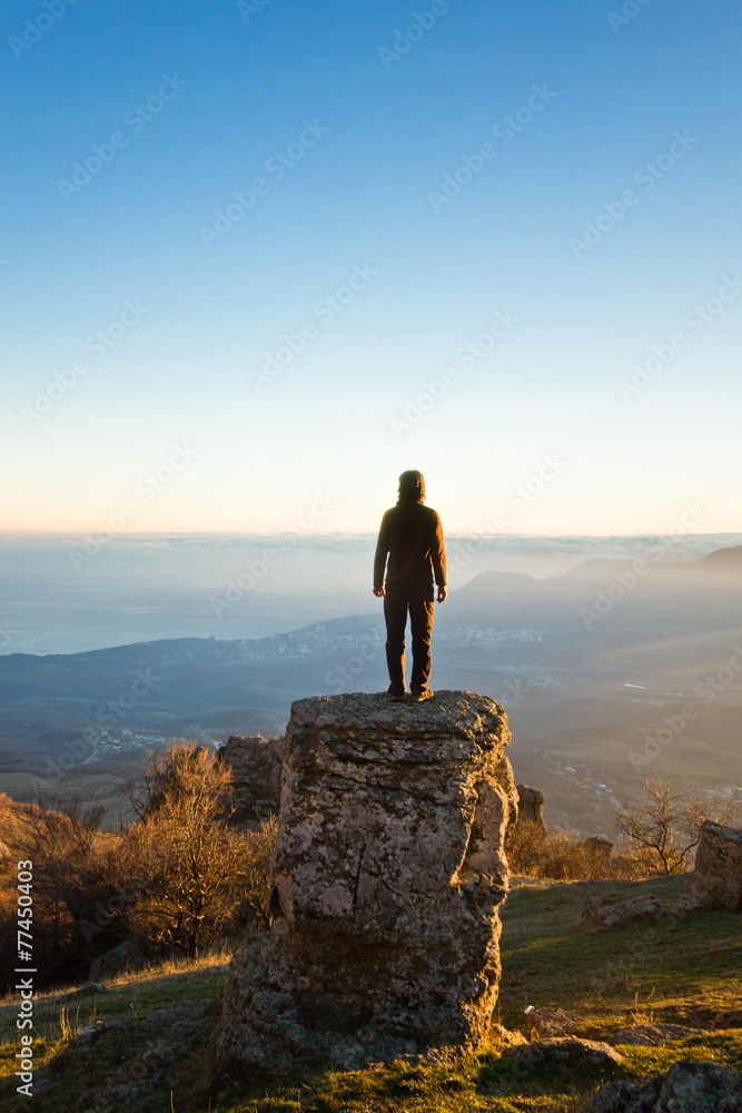 man on the cliff in mountains at sunset