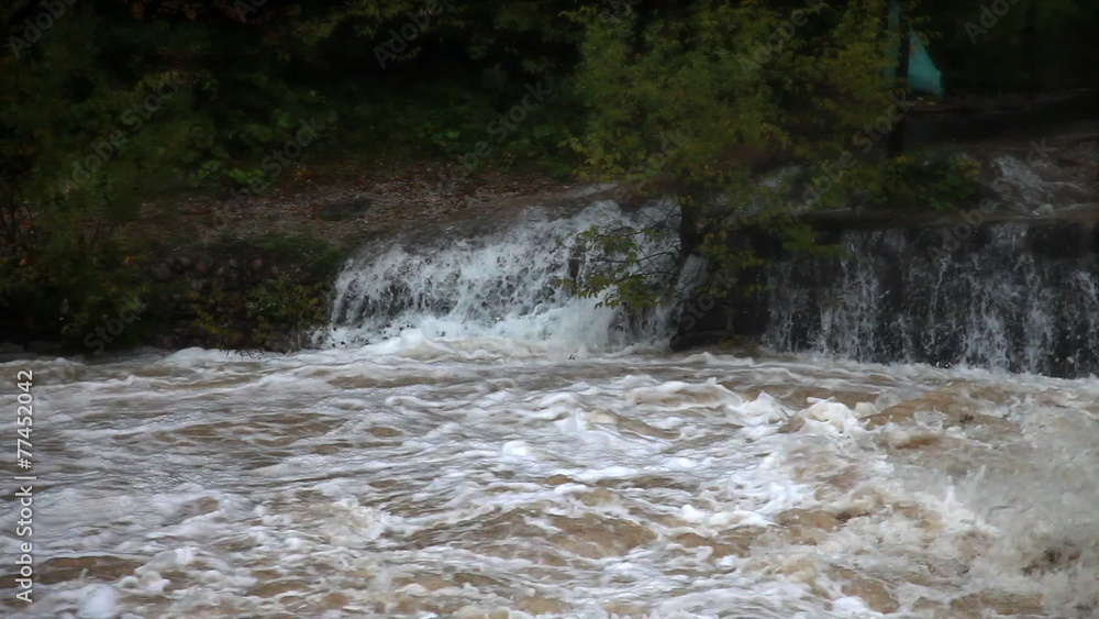 Wiew of the mudy restless river with a small cascade in the back Wiew of the mudy restless river with a small cascade in the back