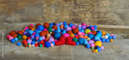 multicolored felted beads and red boots on the wooden background