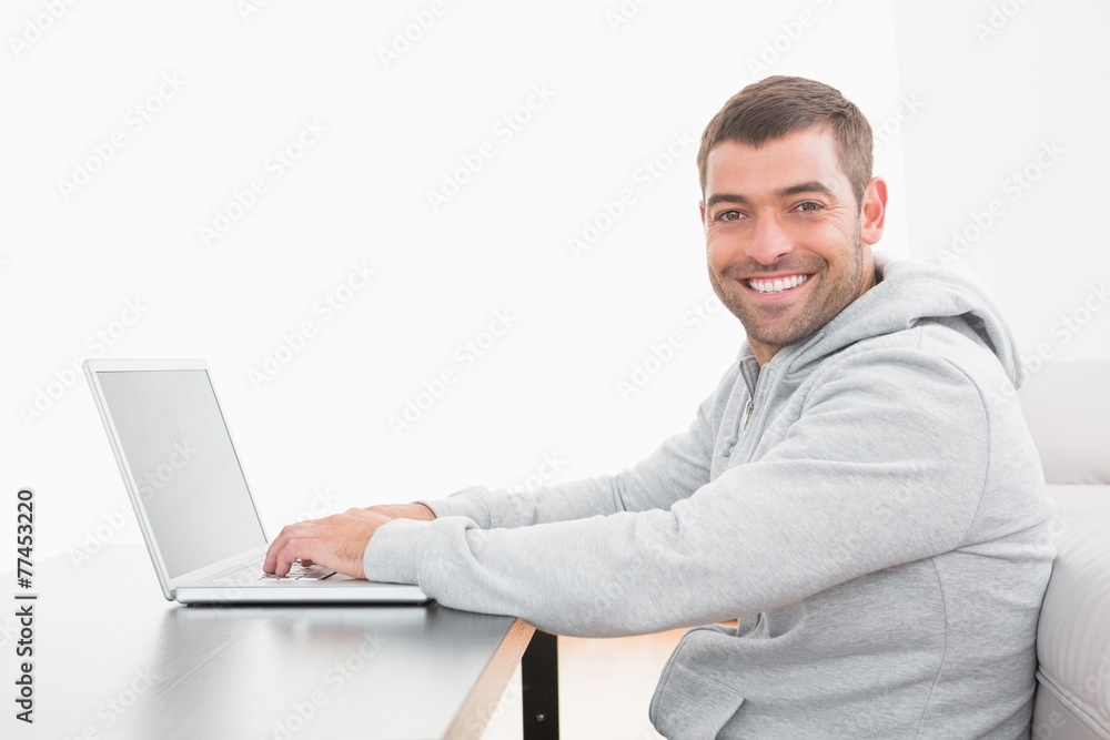 A smiling man using laptop at a table A smiling man using laptop at a table
