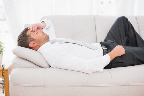 A businessman lying on the sofa at home
