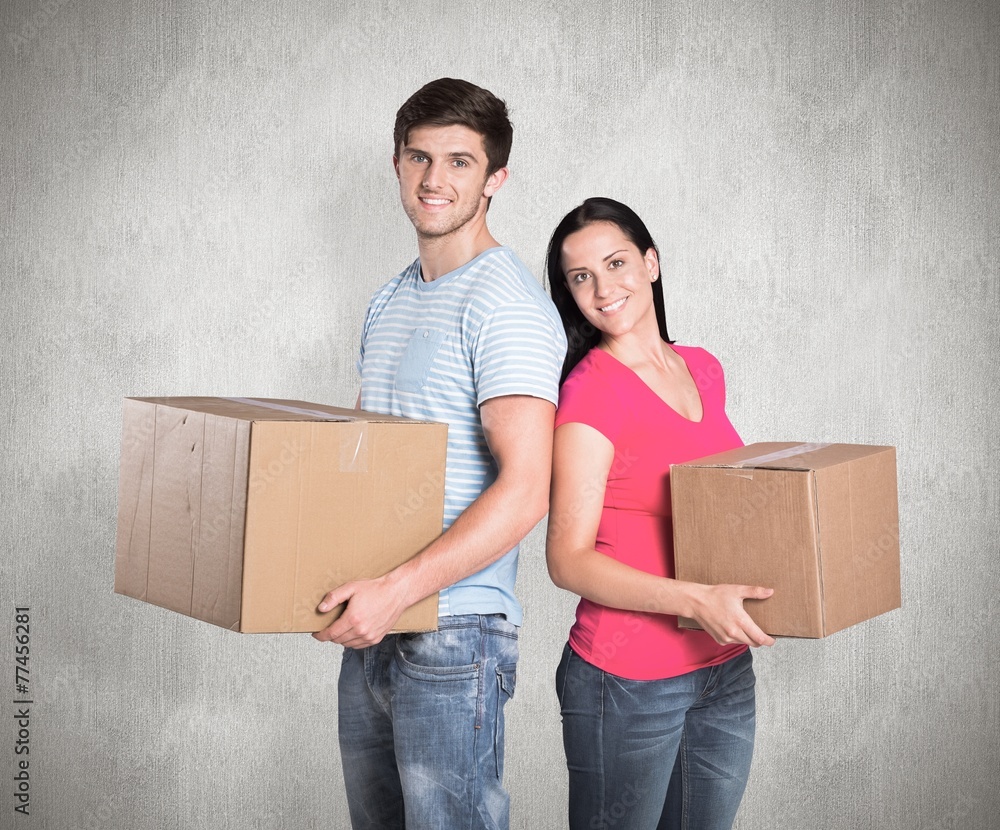 Composite image of young couple holding moving boxes Composite image of young couple holding moving boxes