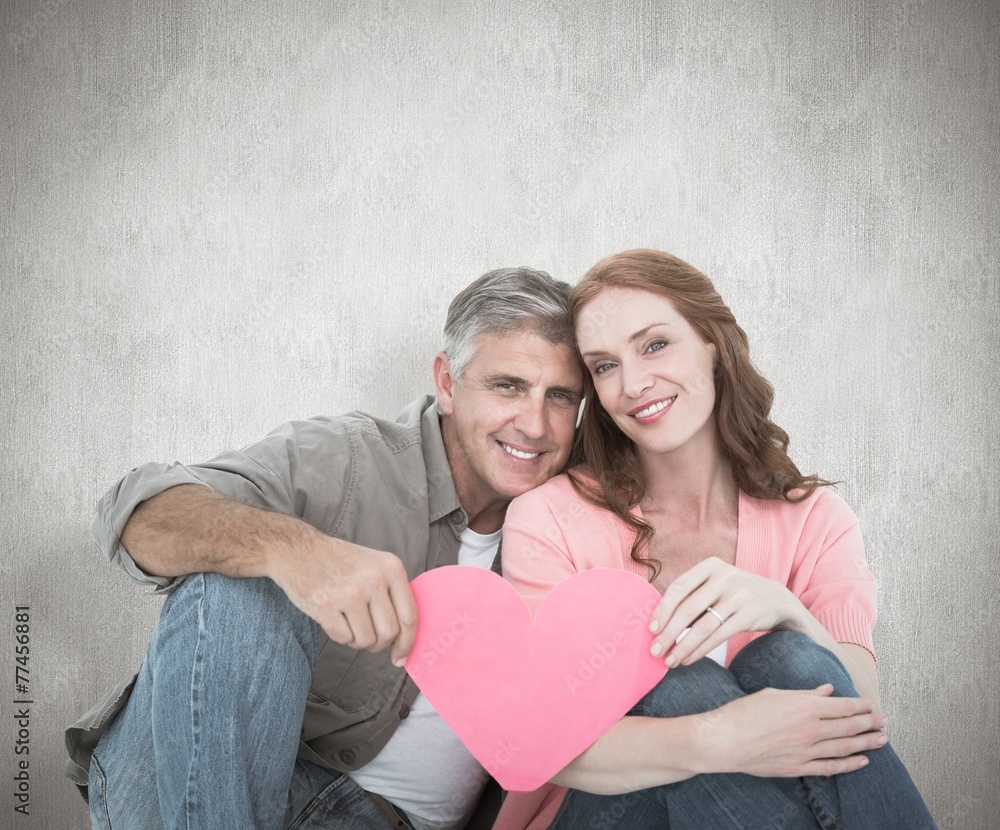 Composite image of casual couple holding pink heart